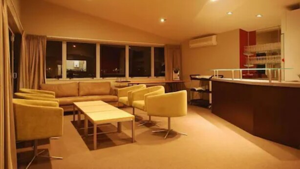 A hotel lobby with a sofa set, armchairs, a coffee table, and a reception desk. - Park View Motor Lodge (Hamilton)
