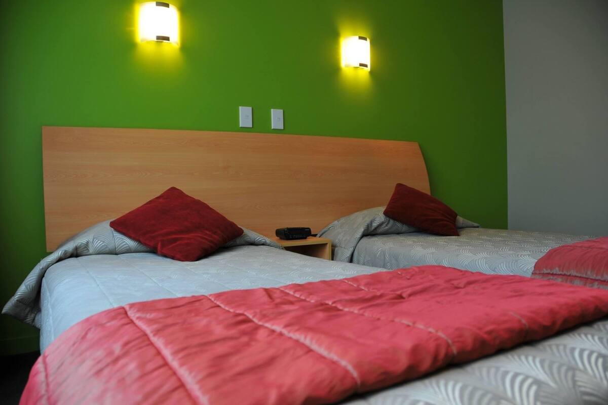 A double bed with a wooden headboard, two bedside tables, and two wall-mounted lights.