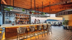 A bar area with wooden flooring, bar stools, and shelves stocked with bottles. - Grand Kaptan Hotel - Ultra All Inclusive (Alanya)