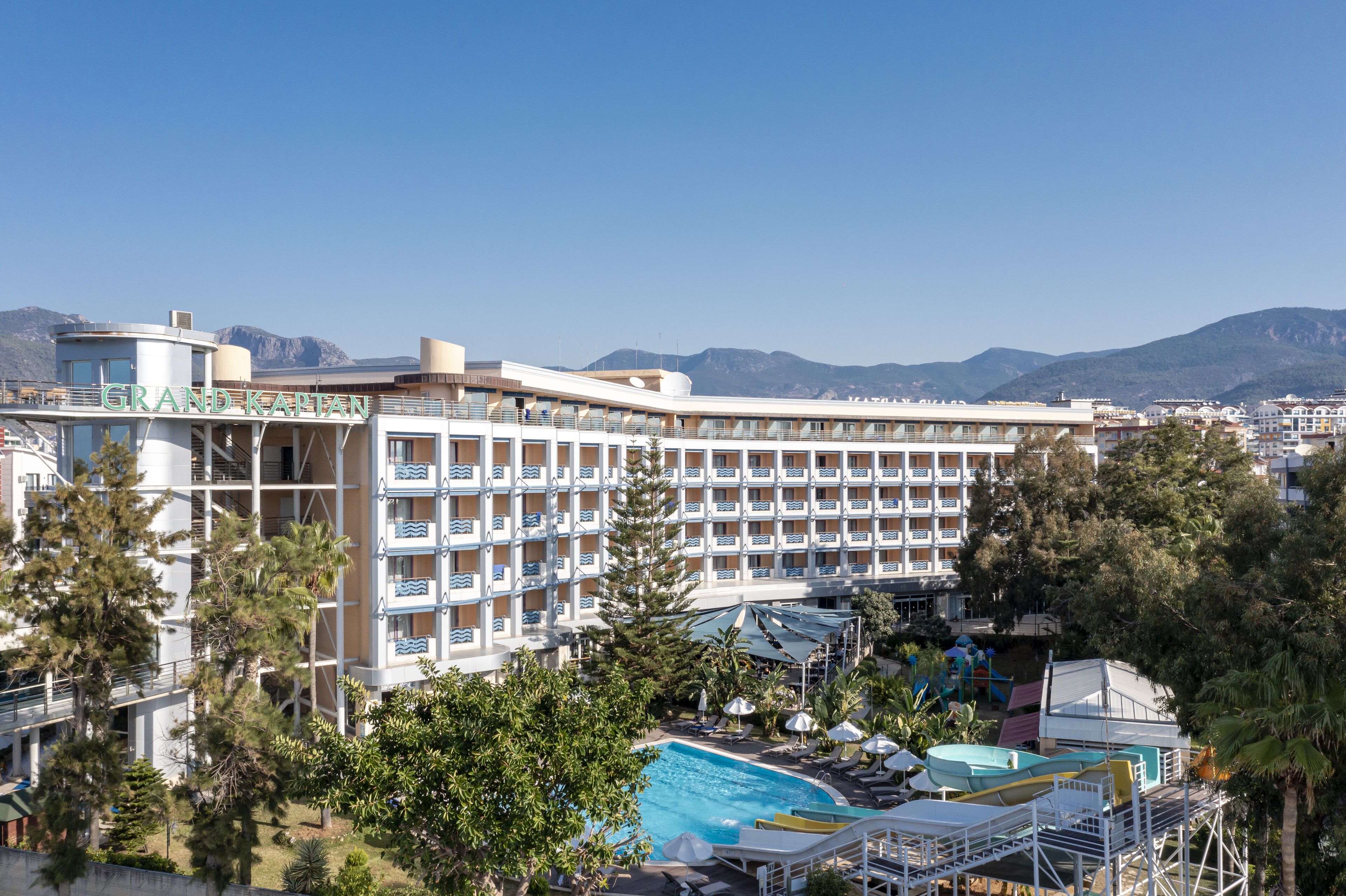 Ein Hotel mit mehreren Etagen, einem Schwimmbad und Bergblick im Hintergrund.