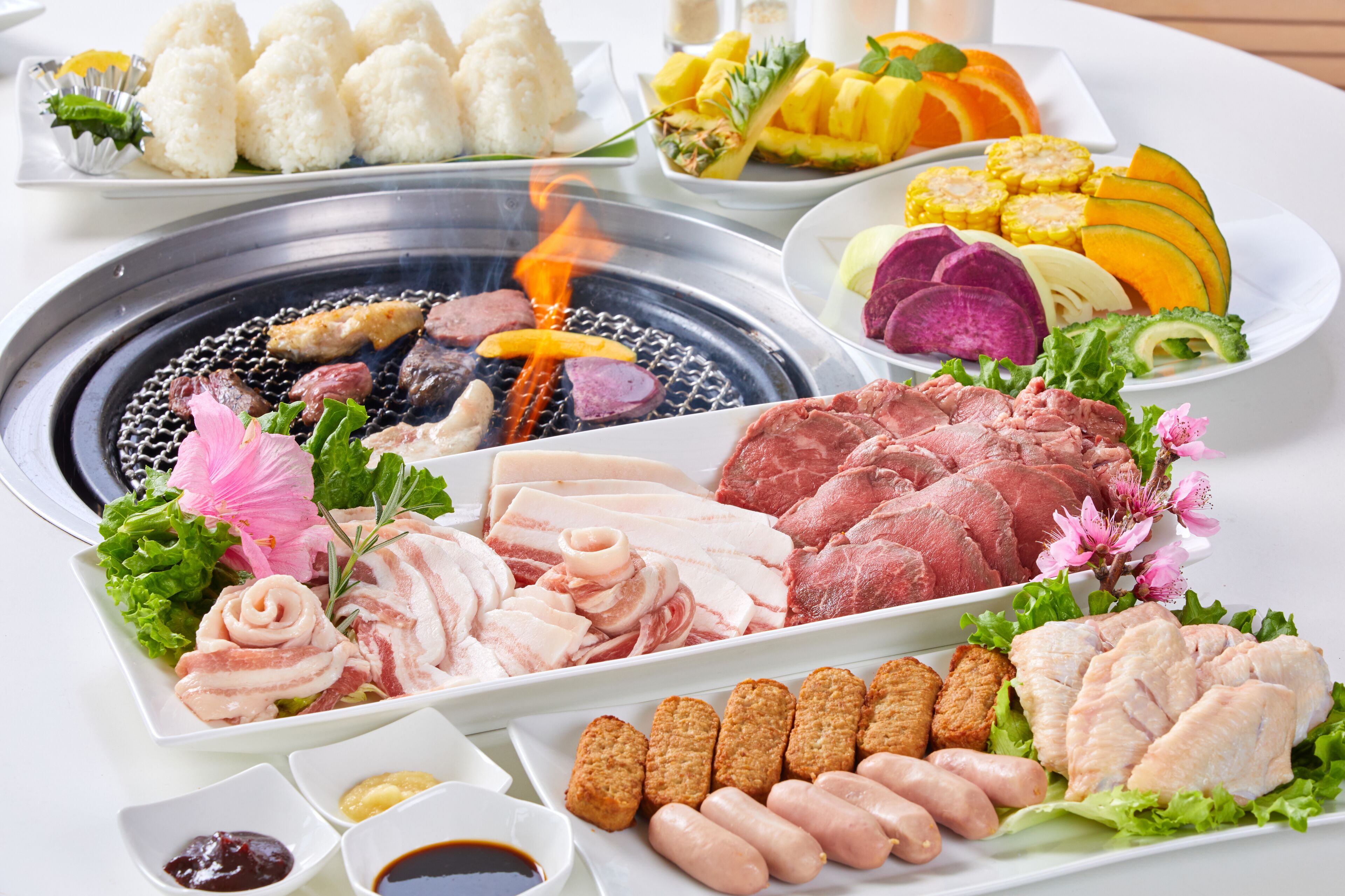 A variety of food items including meats, vegetables, and rice dishes, arranged on a table with a grill in the center.