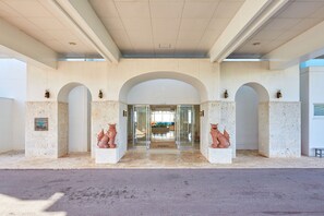 A hotel entrance with a modern design, featuring a large arched doorway and two statues on either side. - Royal View Hotel Churaumi - Closest to Churaumi (Motobu)