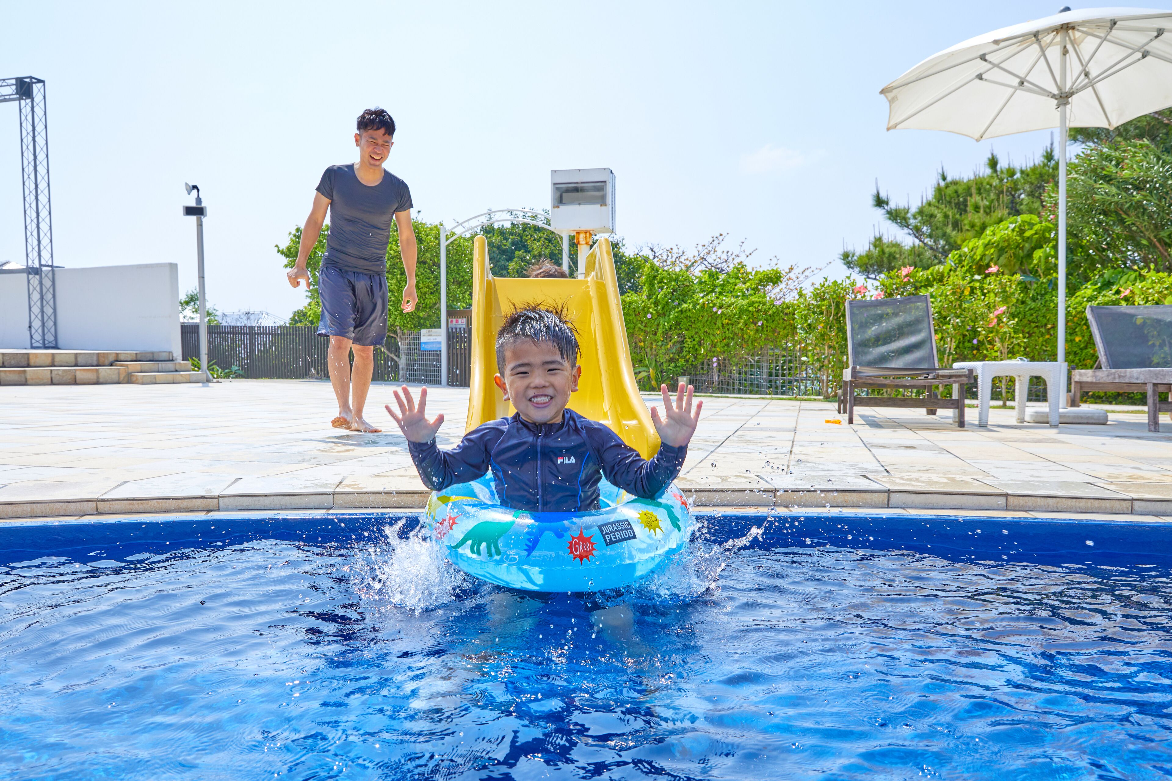 Una piscina con un niño en un flotador y un adulto cerca.