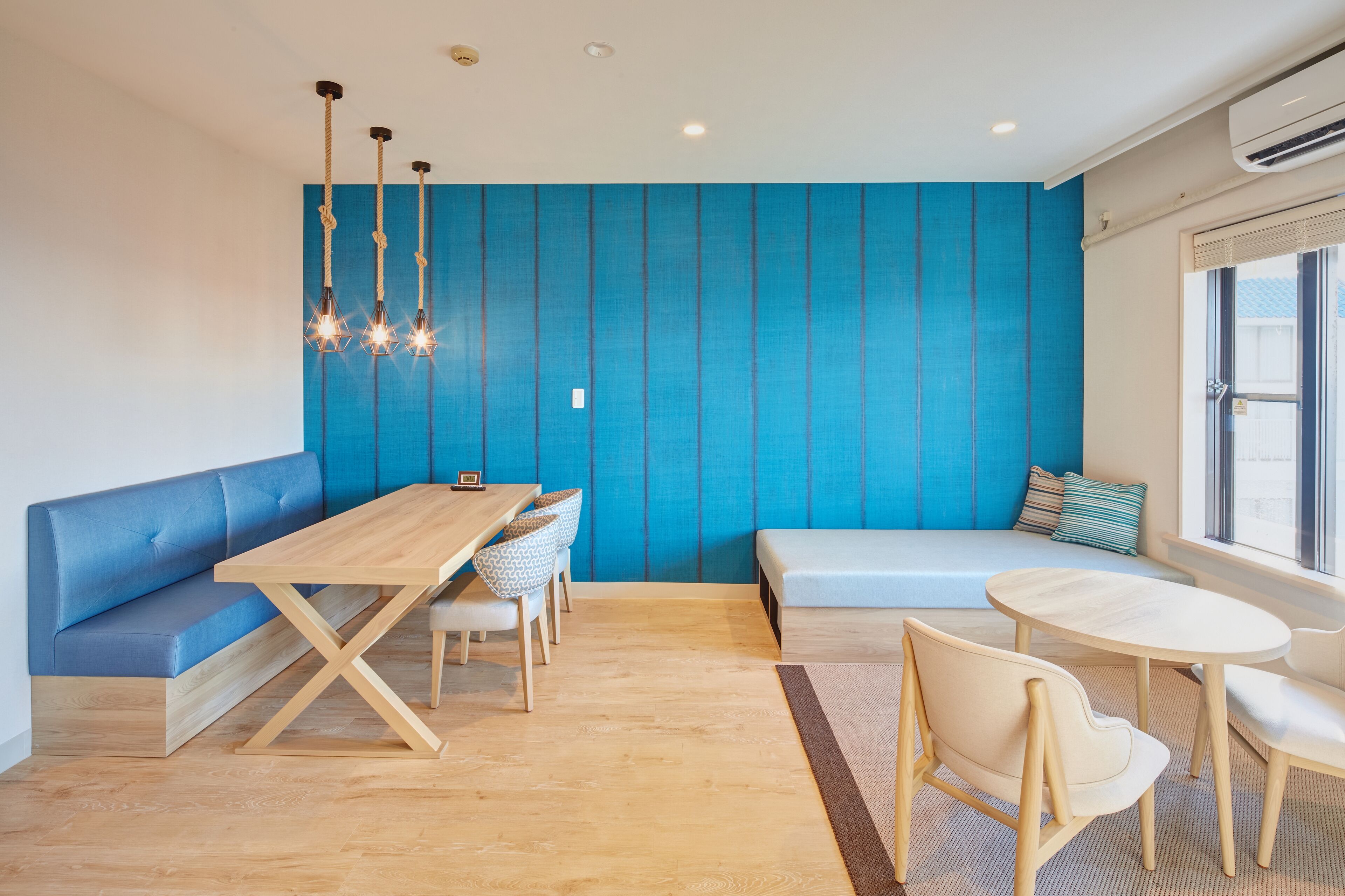 A modern interior with a blue accent wall, wooden furniture, and a seating area with a view.