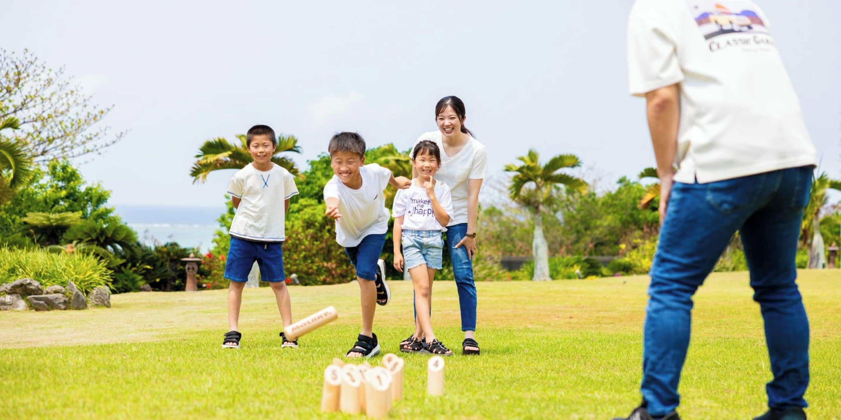 A group of people playing a game outdoors with a grassy field and trees in the background.