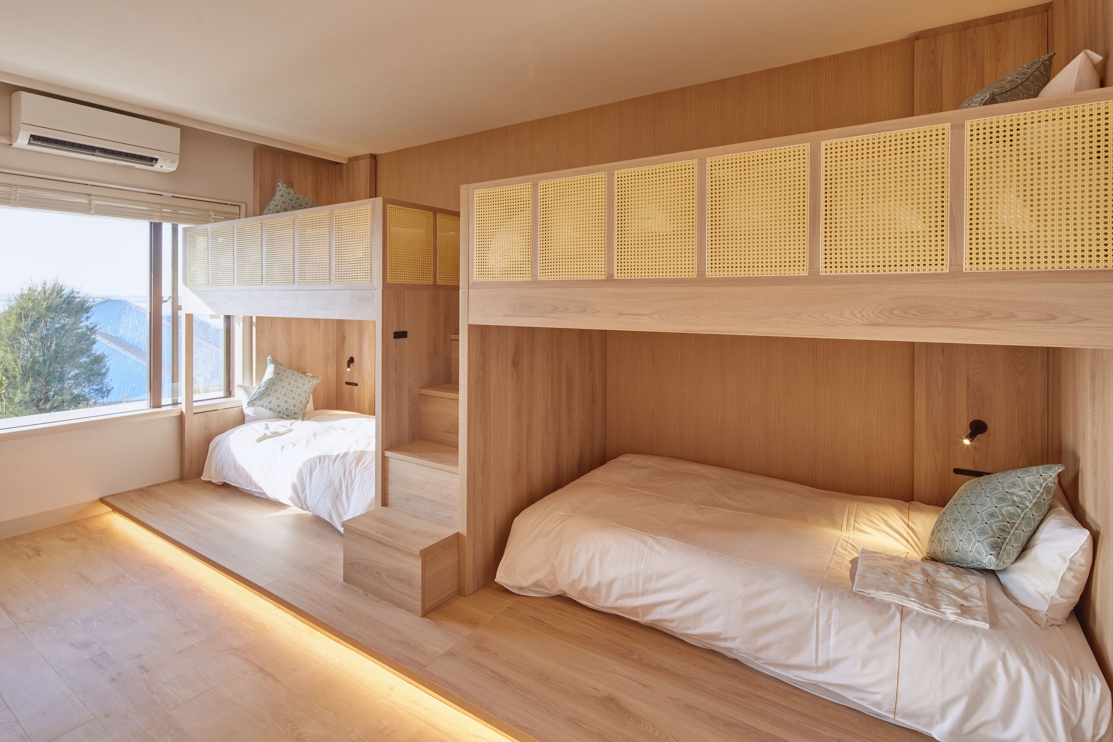 A modern bedroom with bunk beds, wooden paneling, and a large window.