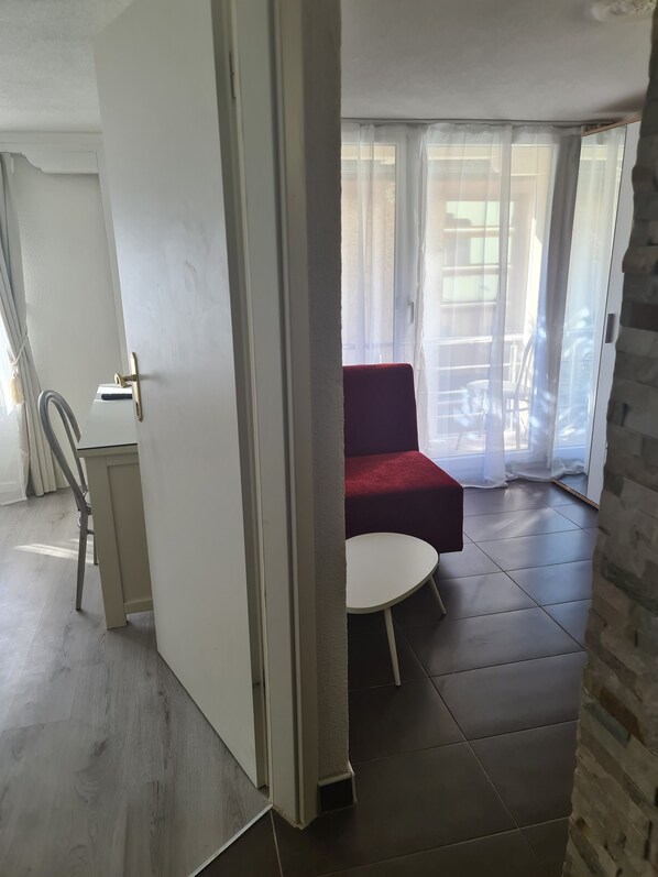 Una habitación con un sofá rojo, una mesita redonda y vistas al exterior a través de cortinas translúcidas.