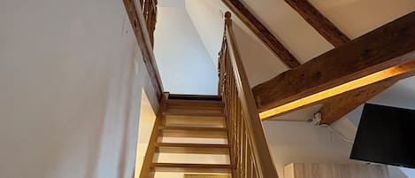 Una escalera de madera que da a una zona de cocina en la parte superior.