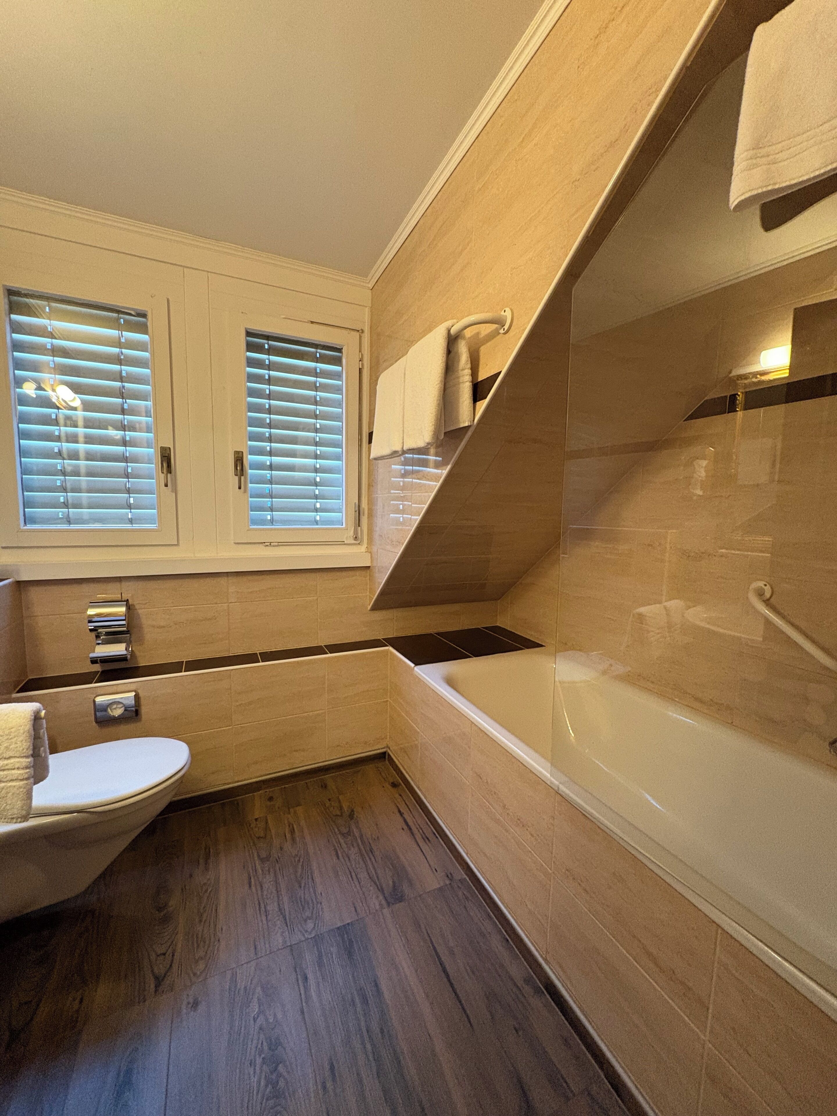 Un baño moderno con bañera, inodoro y persianas.