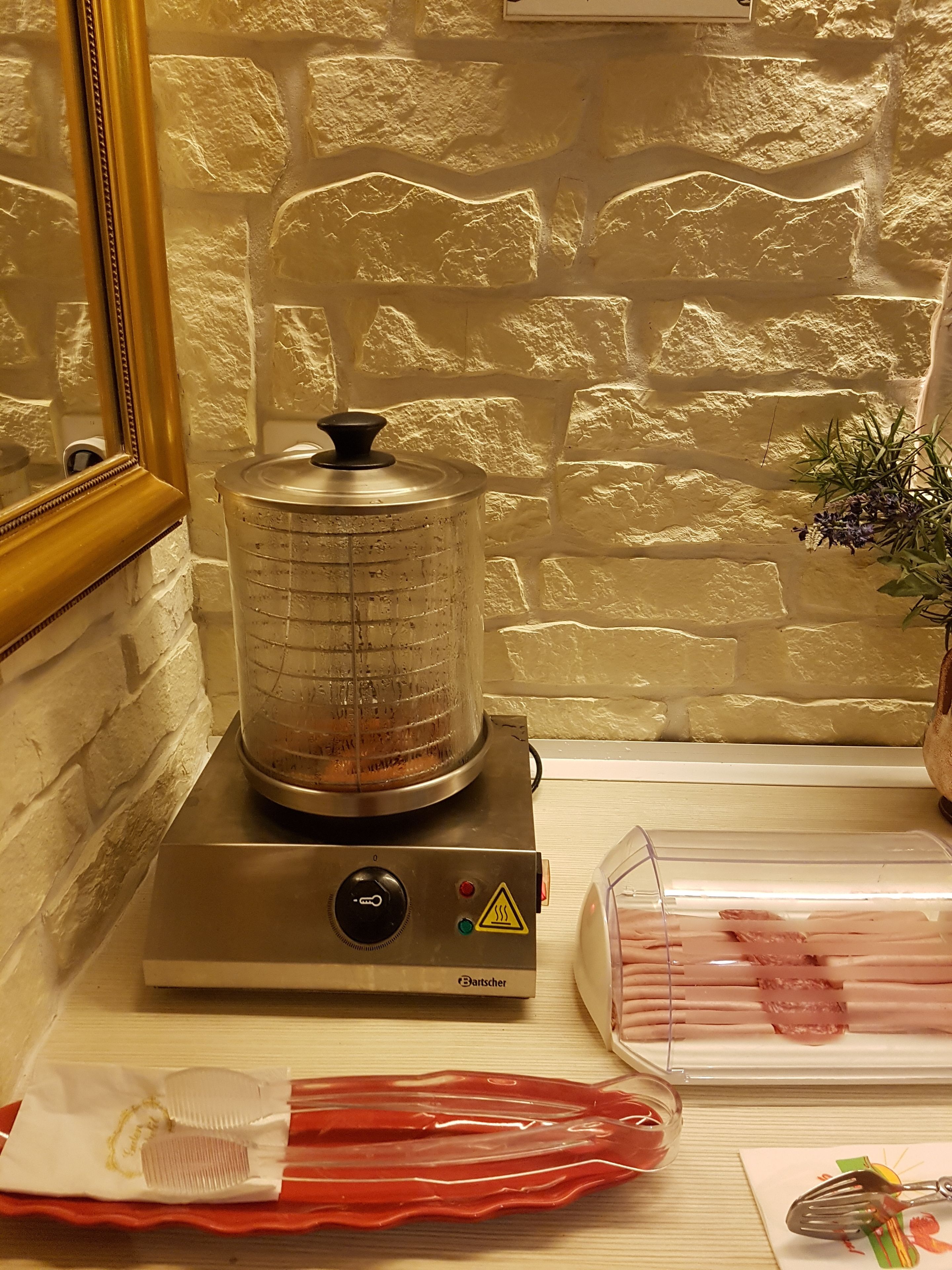 A kitchen with a food processor, a plastic container with meat, and a red plastic dish.