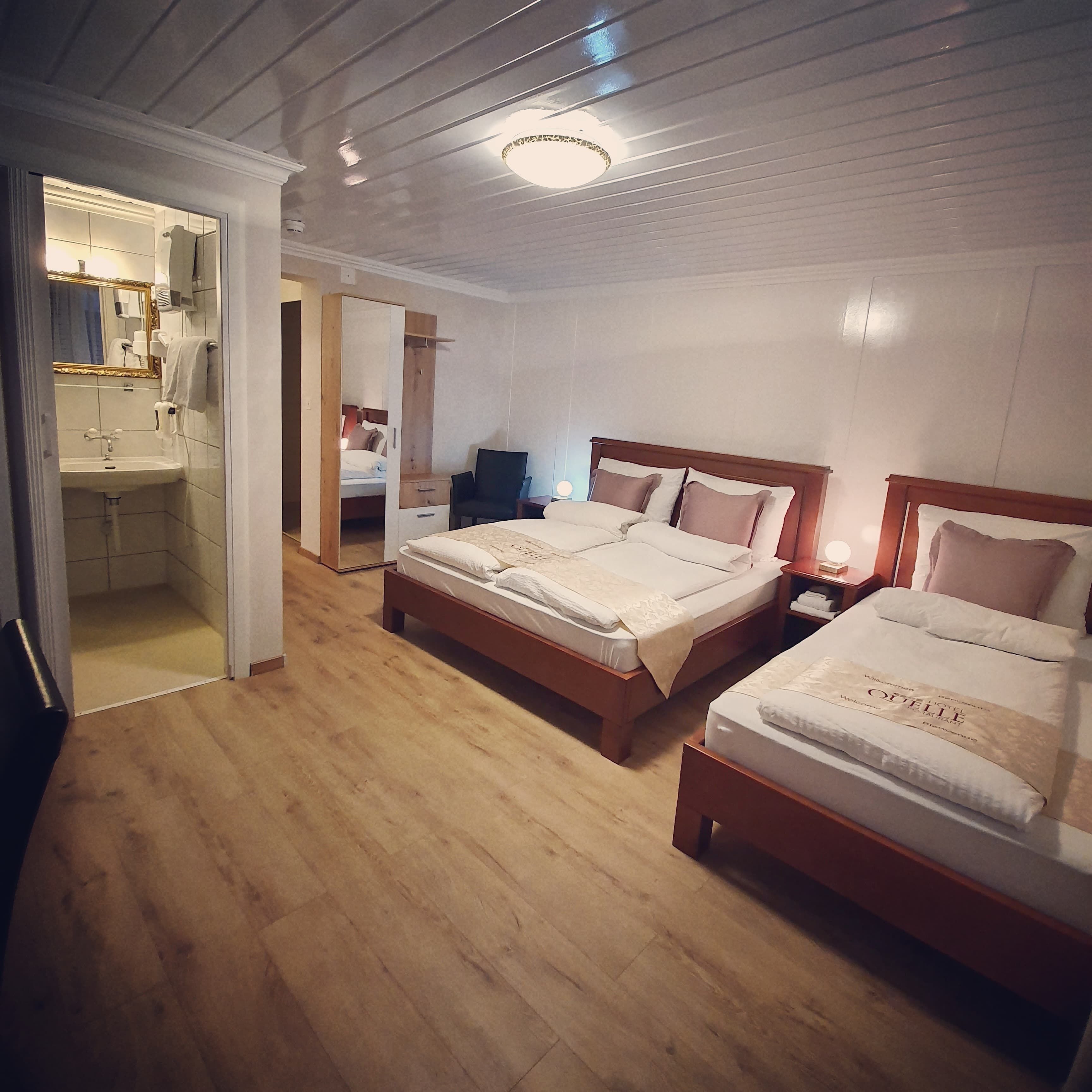 Une chambre d’hôtel avec deux lits, une salle de bain et un miroir.