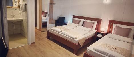 Habitación de hotel con dos camas, un baño y un espejo.