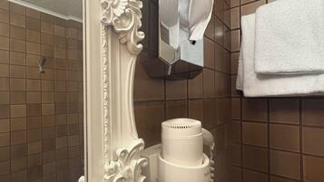 A bathroom with a white ornate mirror, a hairdryer, and a towel rack.