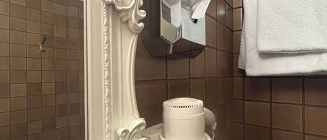 A bathroom with a white ornate mirror, a hairdryer, and a towel rack.