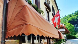 Een hotel met terras, een Zwitserse vlag en een bord met de naam Hotel Quolle Esos.