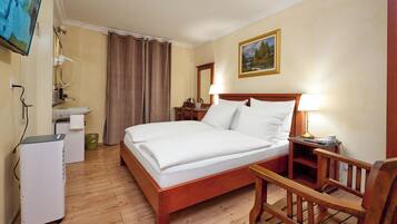 Een hotelkamer met een houten bed, een bureau, een stoel, een televisie en een schilderij aan de muur.