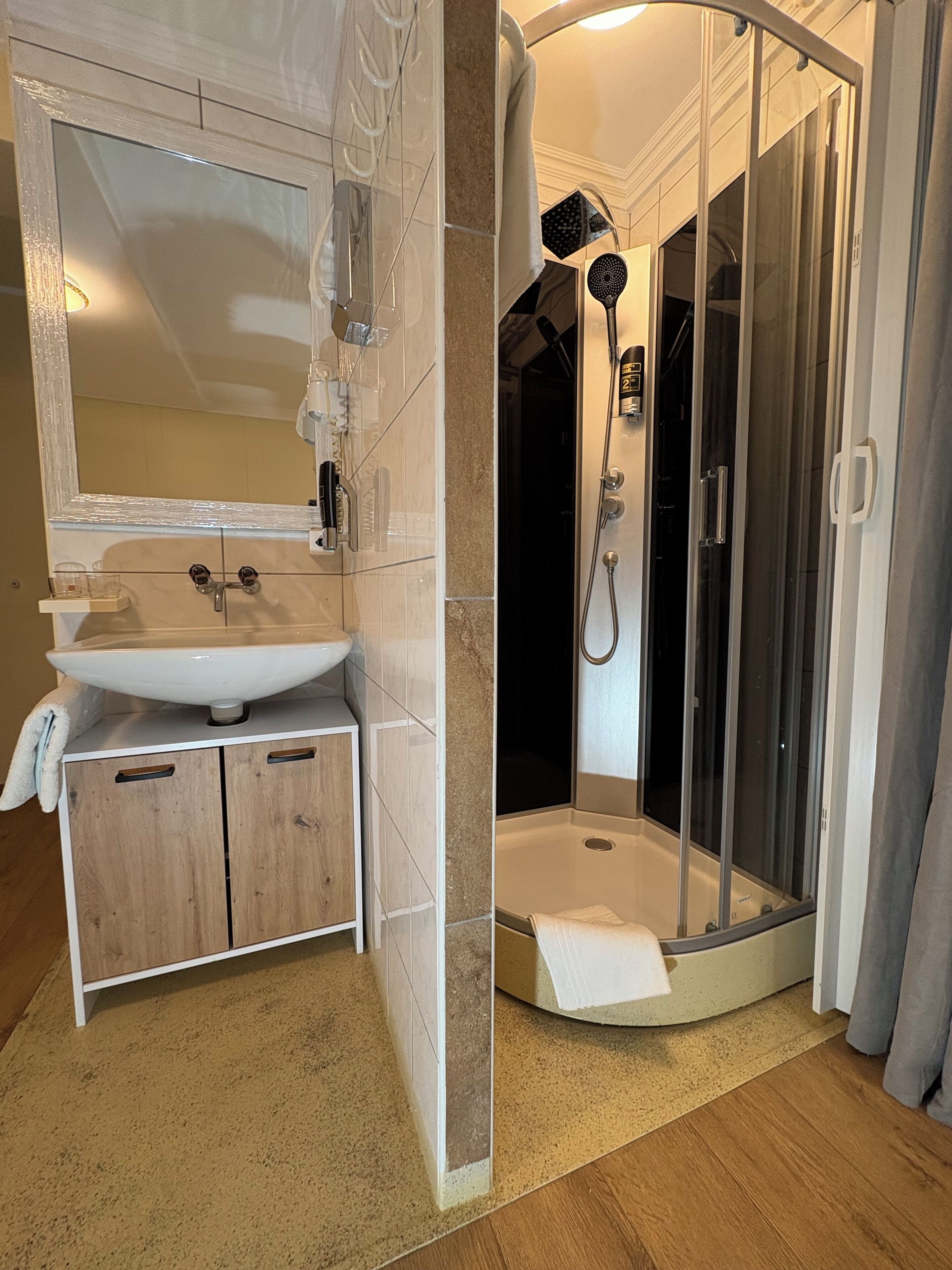 Een moderne badkamer met een wastafel, spiegel en douche.