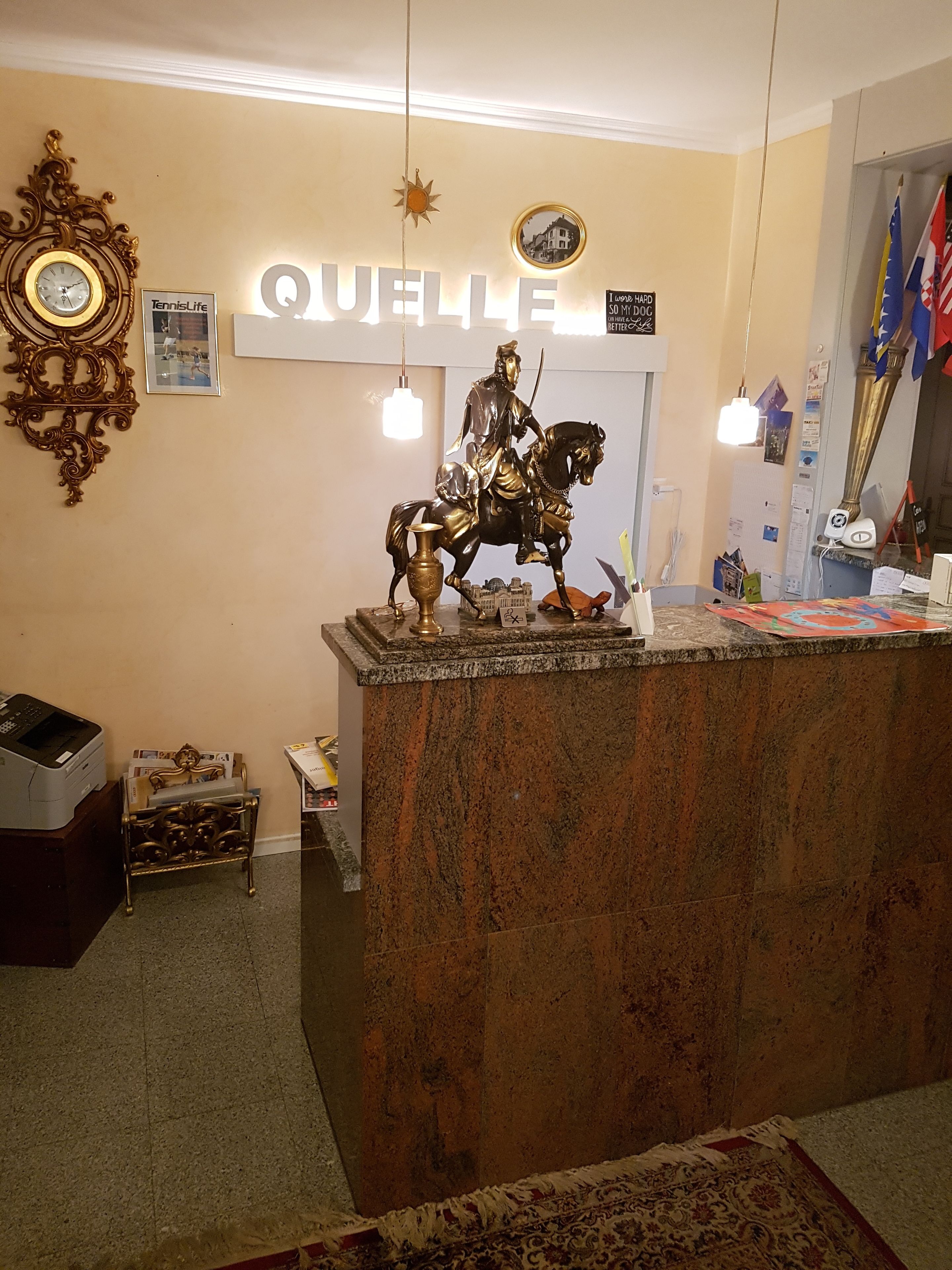 Un mostrador de recepción con una estatua montada de un caballero a caballo, un reloj y un cartel que dice "QUELLE".