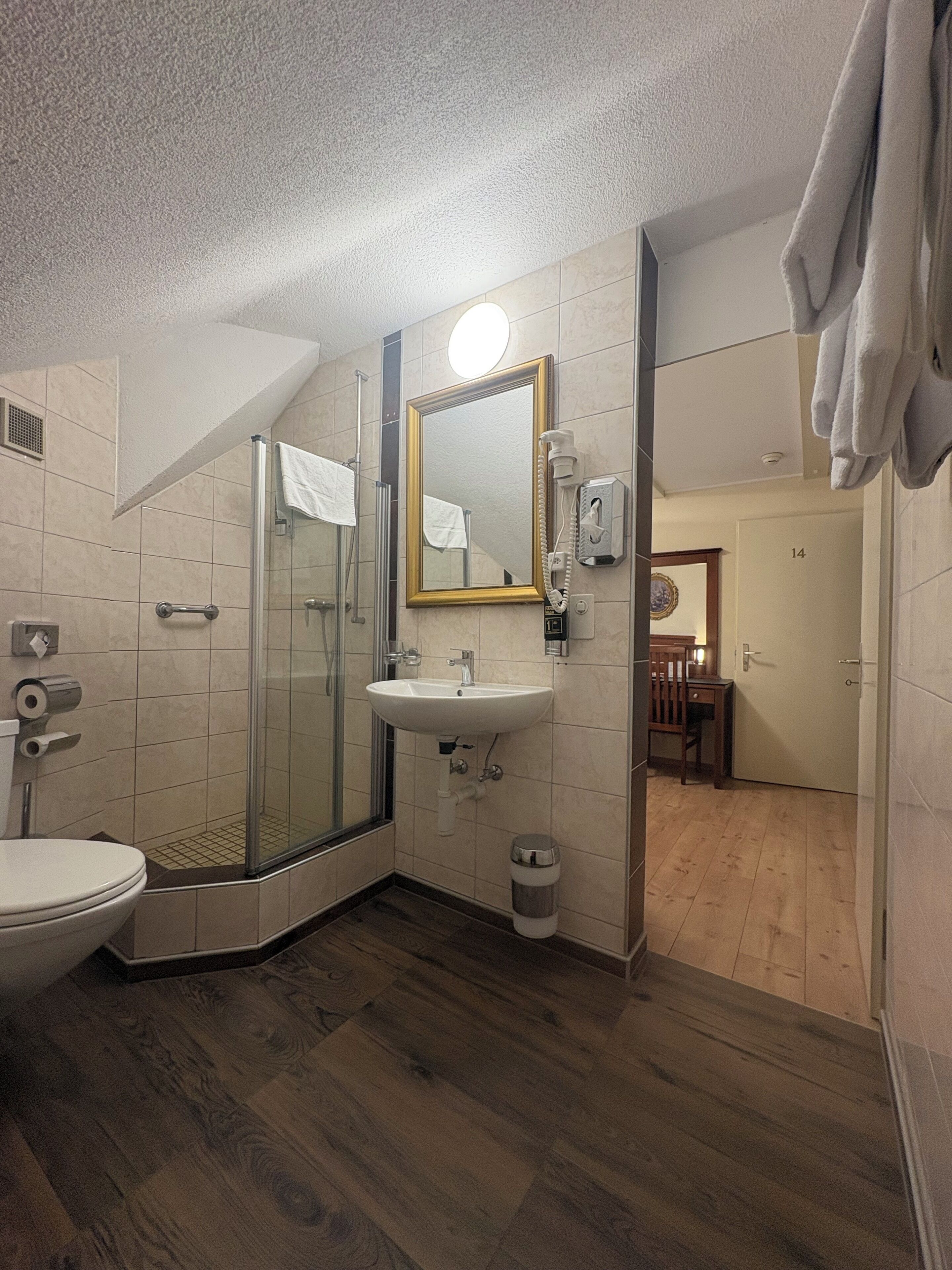 Un baño con cabina de ducha de vidrio, lavamanos e inodoro.