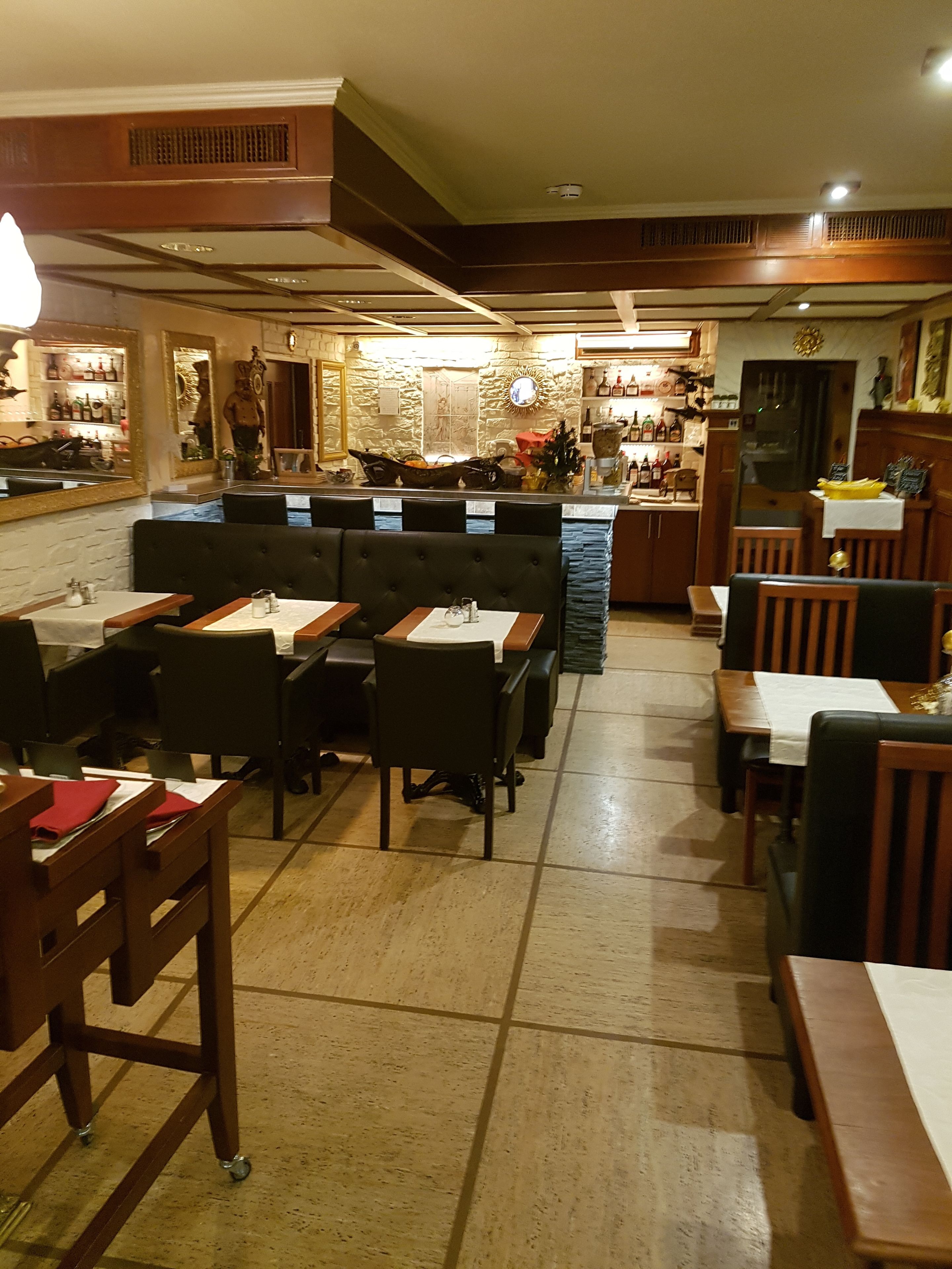 A restaurant interior with booths and tables, a bar area, and a stone wall with a mirror and artwork.