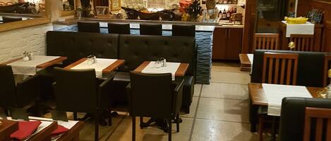 A restaurant interior with booths and tables, a bar area, and a stone wall with a mirror and artwork.
