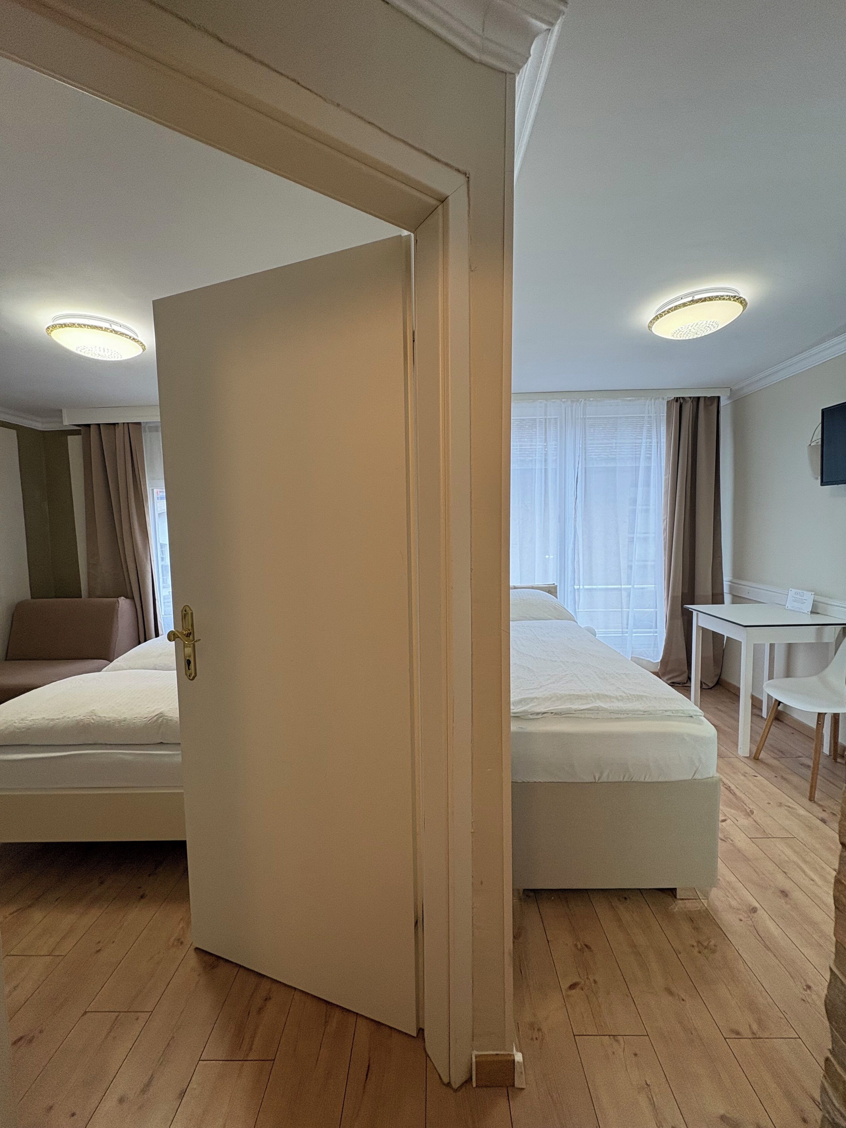 Ein Hotelzimmer mit zwei Betten, einem Schreibtisch und einem Stuhl.