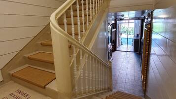 Una escalera con balaustres blancos y peldaños de madera que conduce a una habitación con la leyenda 'ZINIERI 1-3'.