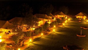 Vista nocturna de un resort con varias tiendas de campaña y senderos bien iluminados.