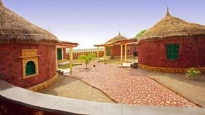 Un patio con edificios de techo de paja tradicional, un sendero pavimentado y un cielo despejado.