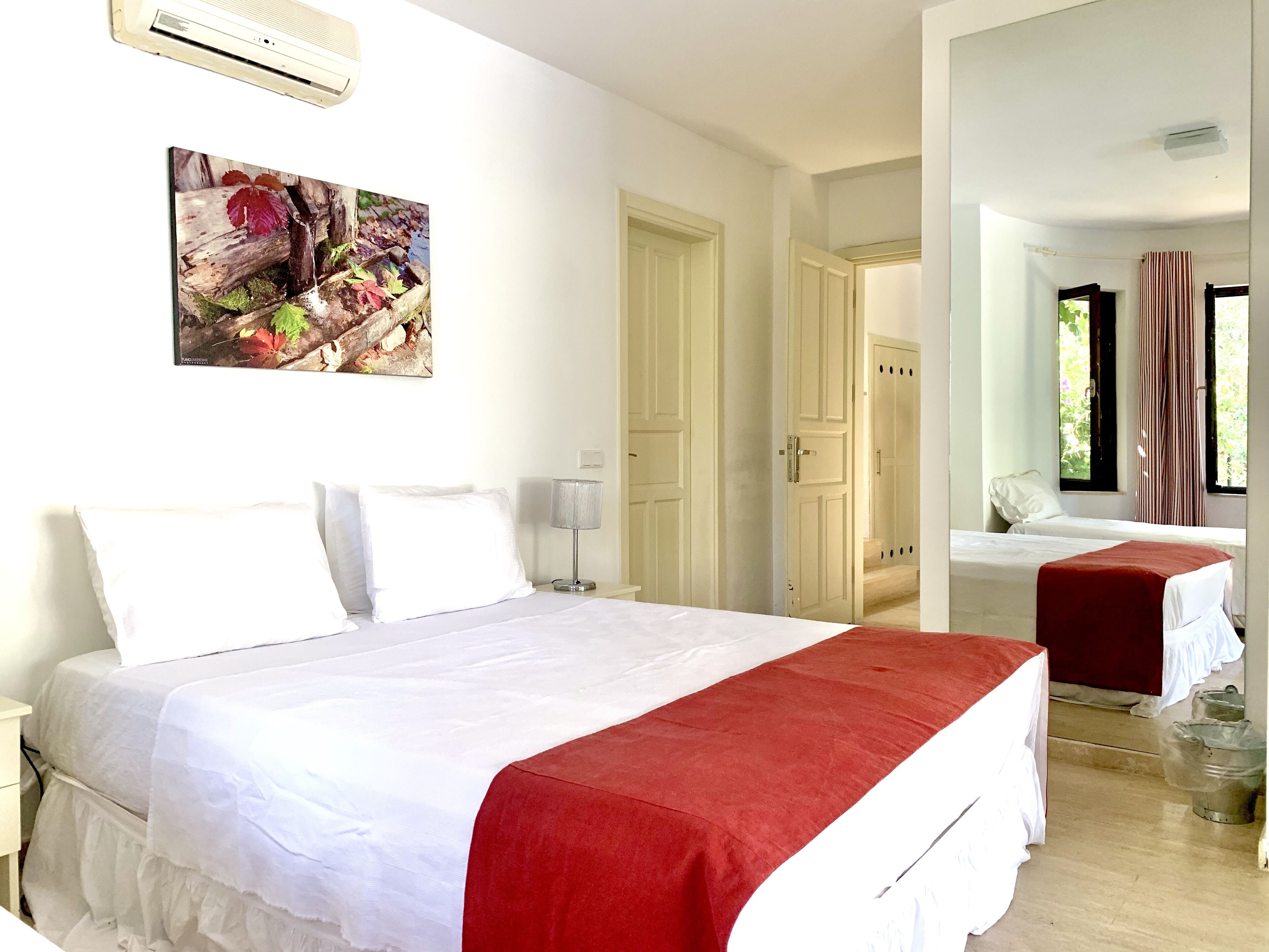 Une chambre d’hôtel avec un grand lit, une table de chevet, une lampe, un tableau et une fenêtre avec des rideaux.
