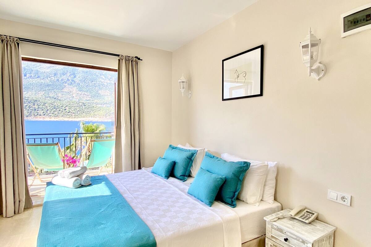 Un dormitorio con cama, una mesita de noche con teléfono, una ventana con cortinas y vistas al exterior.