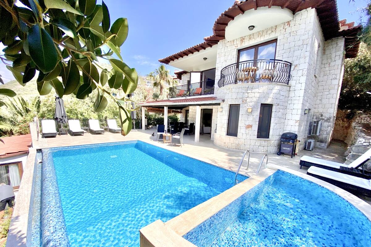 Una piscina con sillas de descanso y un edificio de piedra con balcón.