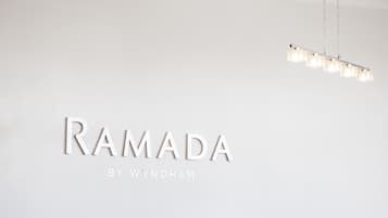 A minimalist wall with the text "RAMADA BY WYNDHAM" and a modern light fixture.