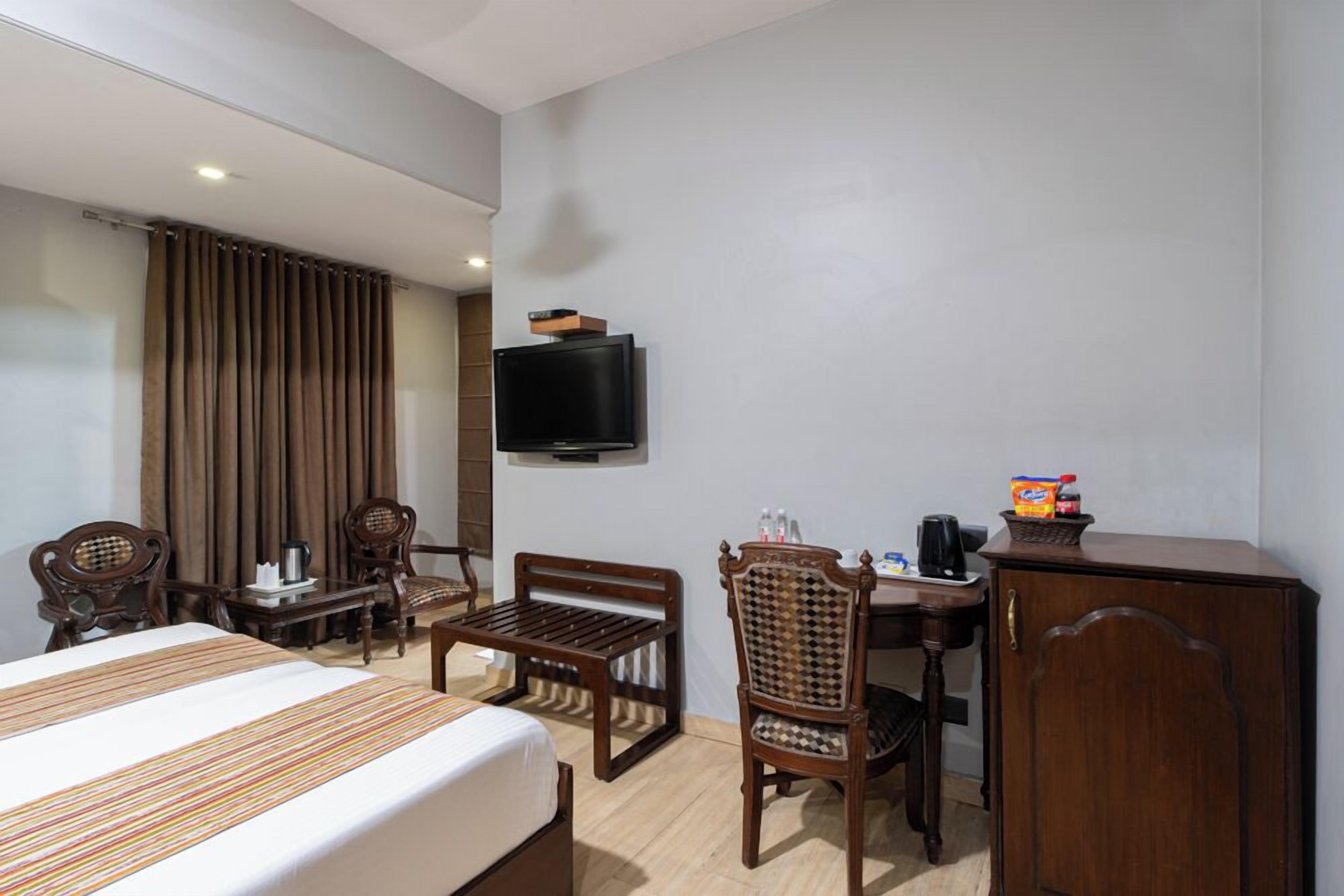 A hotel room with a bed, a desk, a chair, a television, and a cabinet.