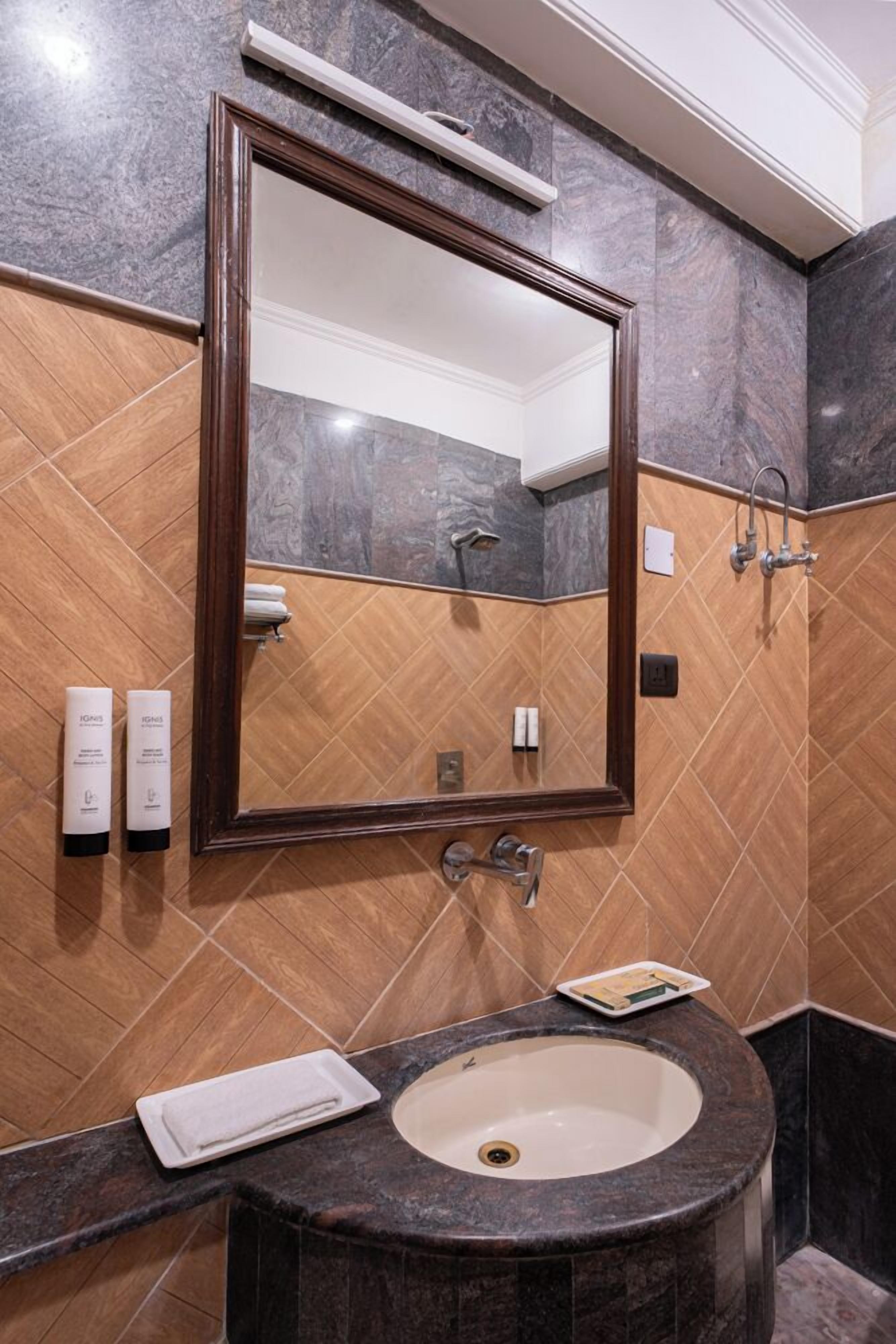 A bathroom with a large mirror, a sink, and a shower.