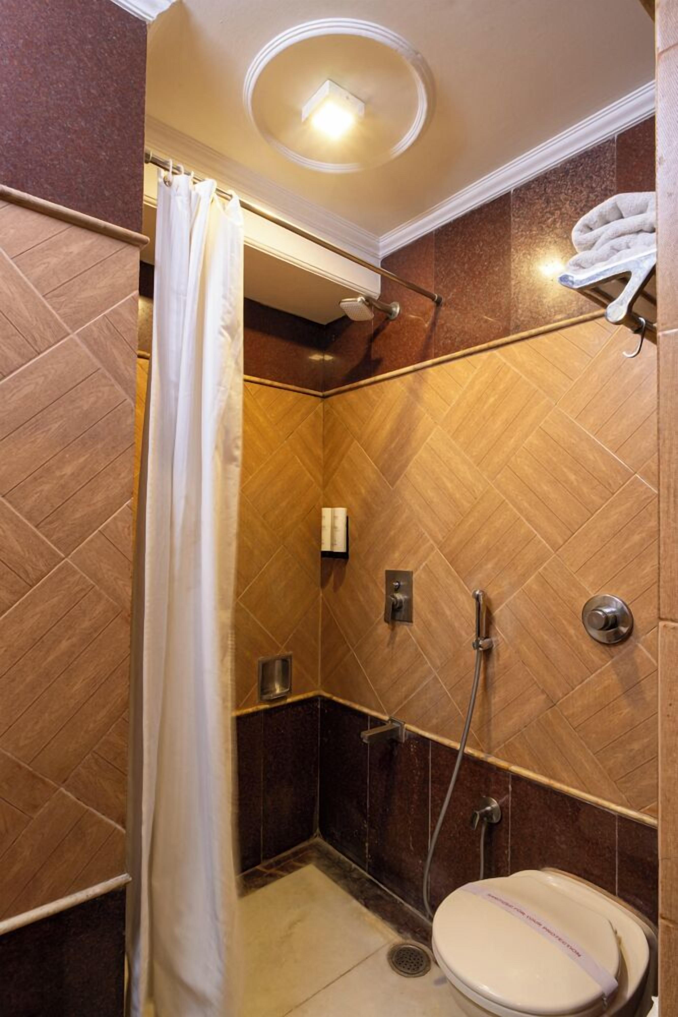 A bathroom with a shower, toilet, and towel rack.