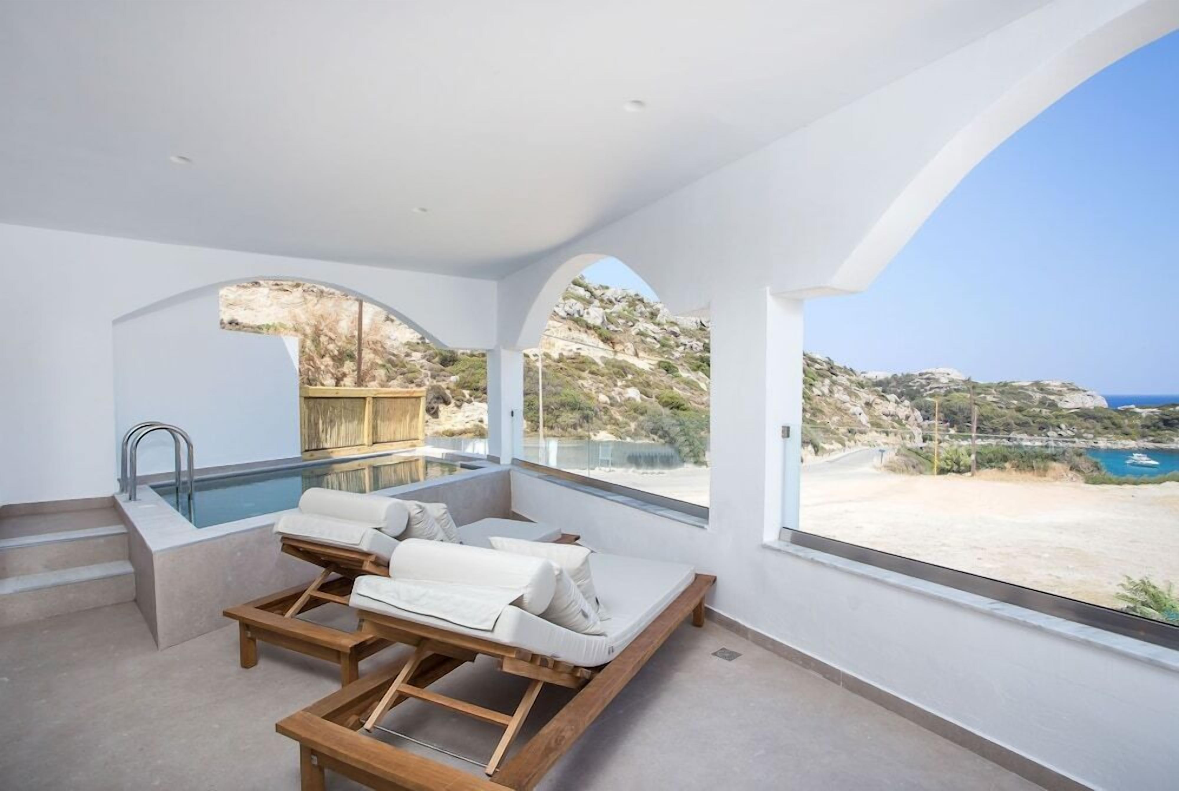 A modern room with a pool, a wooden deck, and a view of the landscape.