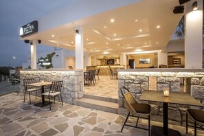 An outdoor seating area with stone walls and tables, a bar in the background, and a sign for Sala Pietra Restaurant. - Ladiko Hotel And Bungalows (Rhodes)