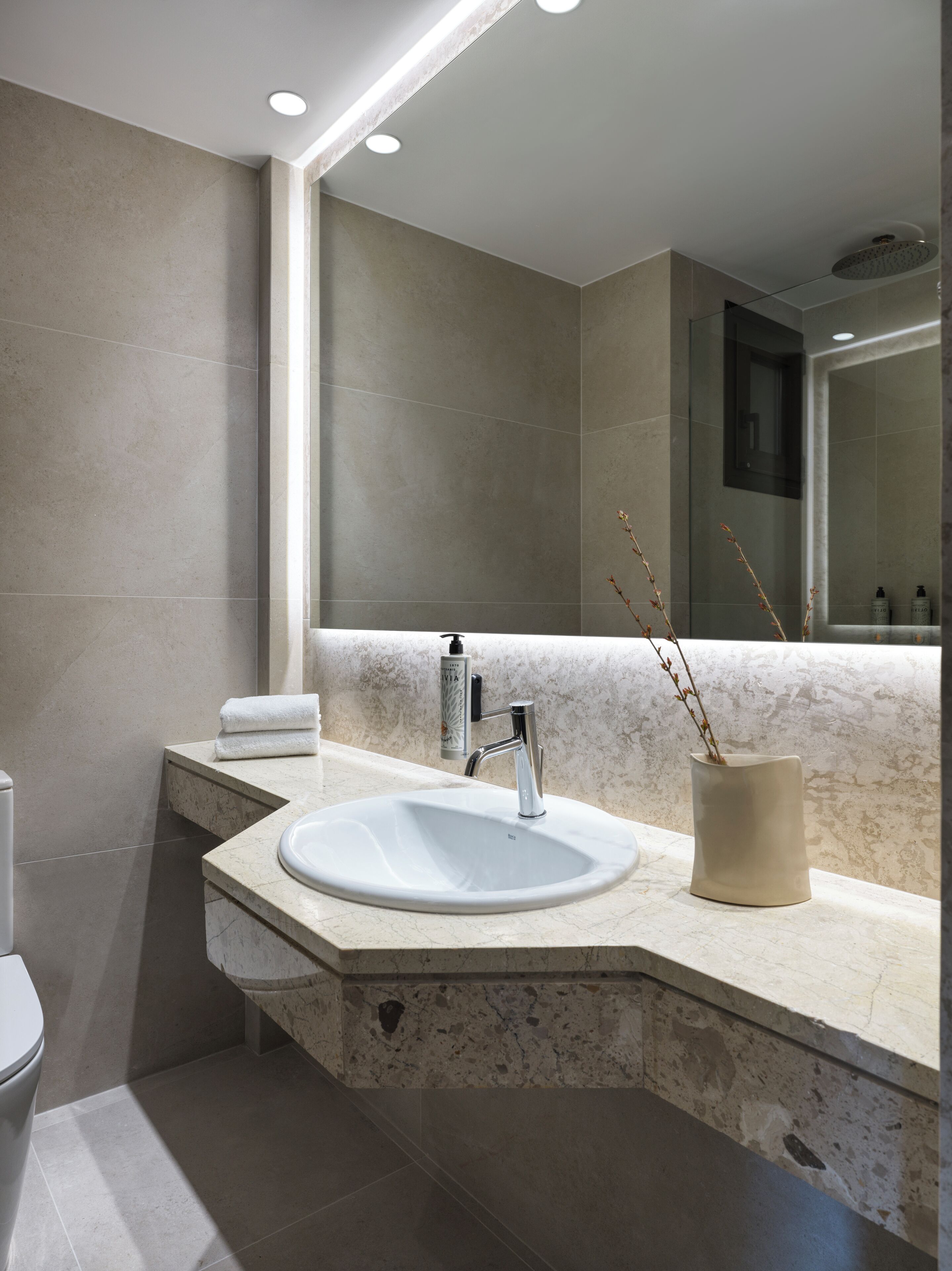 Un baño moderno con un espejo grande, un lavamanos y un inodoro.