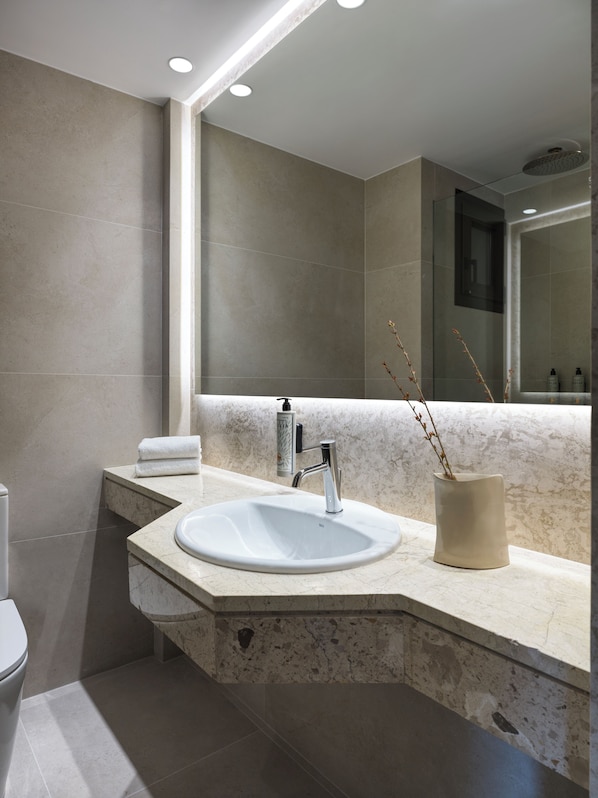 A modern bathroom with a large mirror, a sink, and a toilet.
