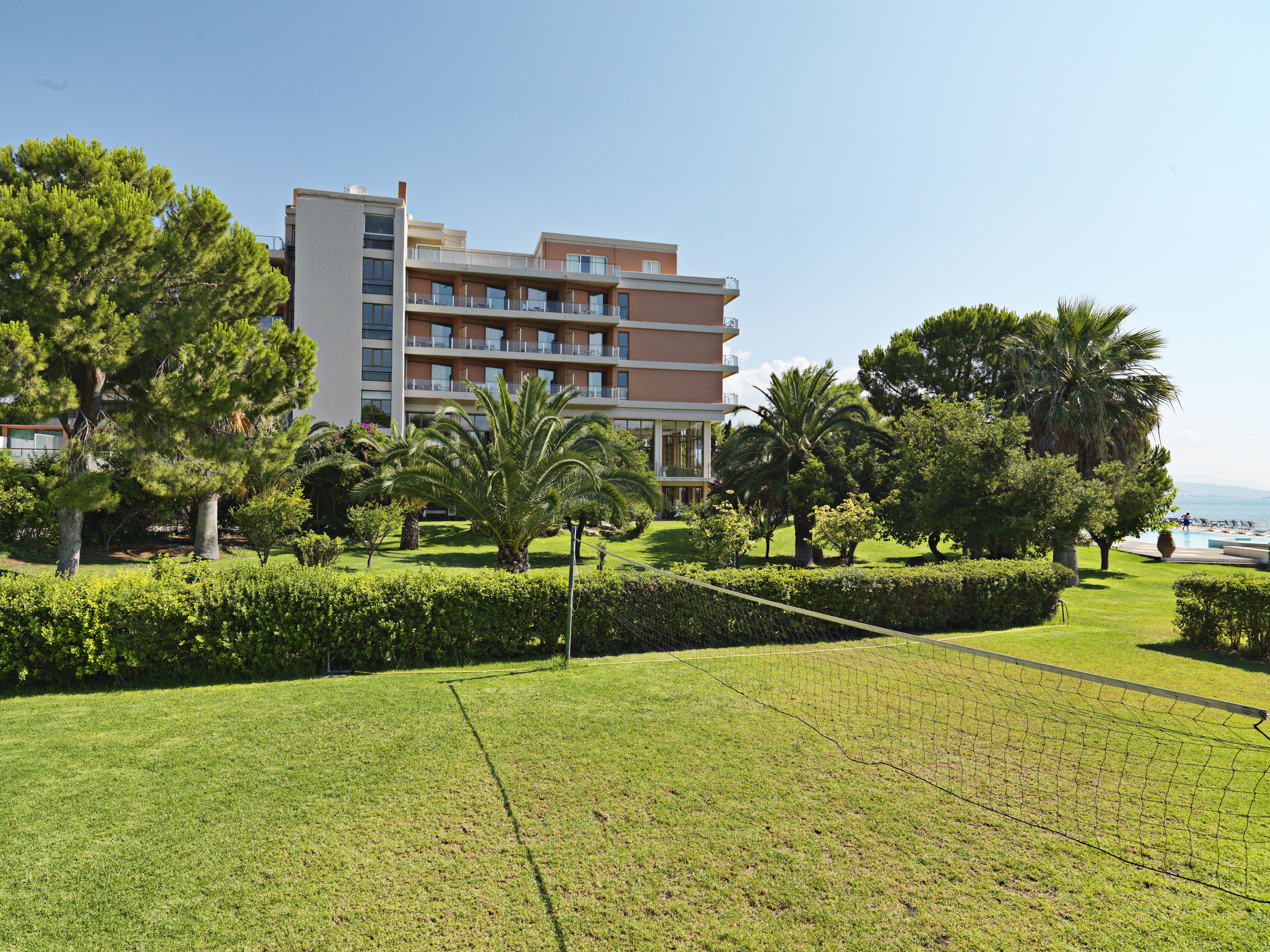 A multi-story hotel with balconies, surrounded by well-maintained lawns and palm trees.