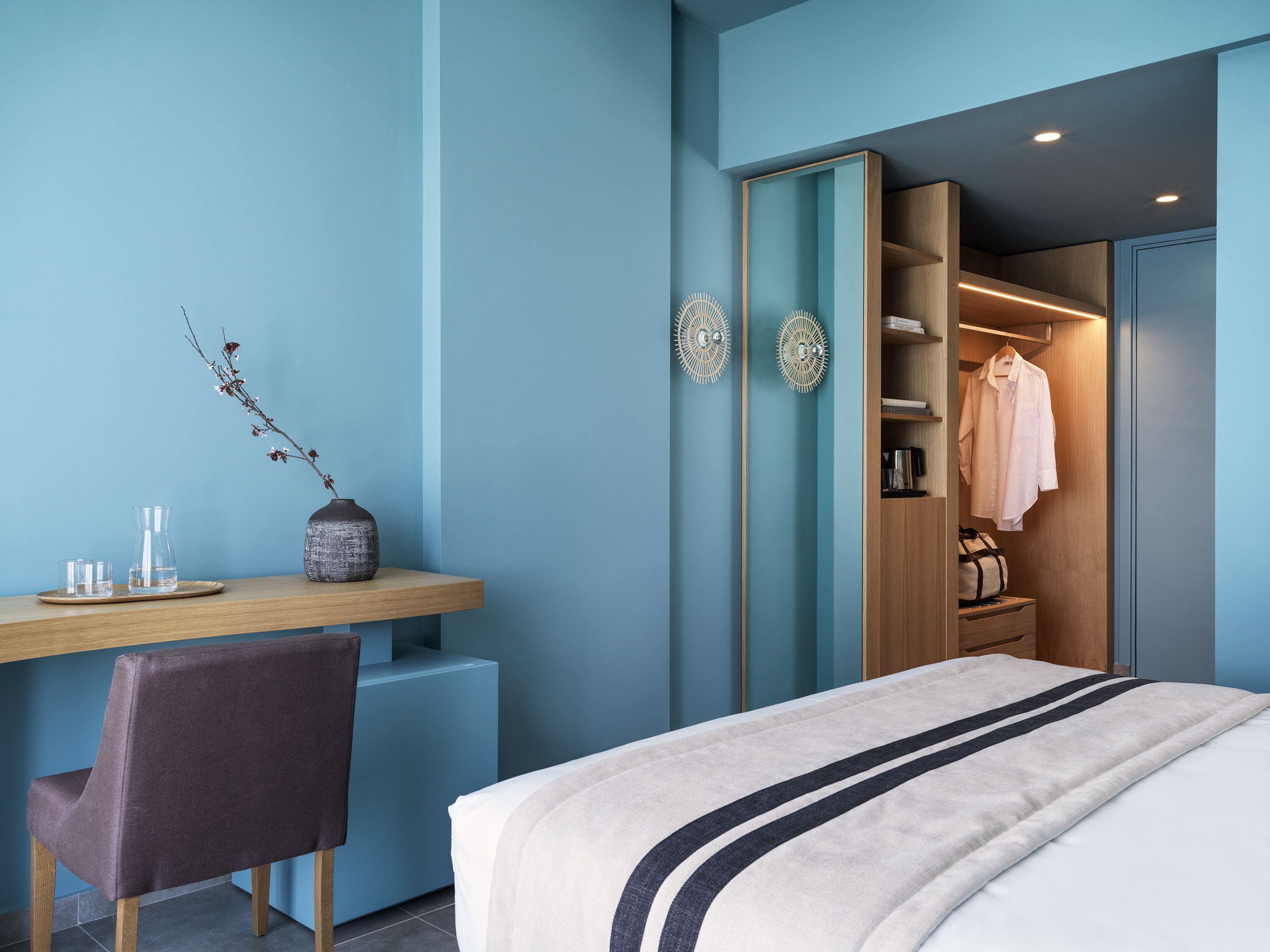 A modern bedroom with a bed, a desk, and a wardrobe.
