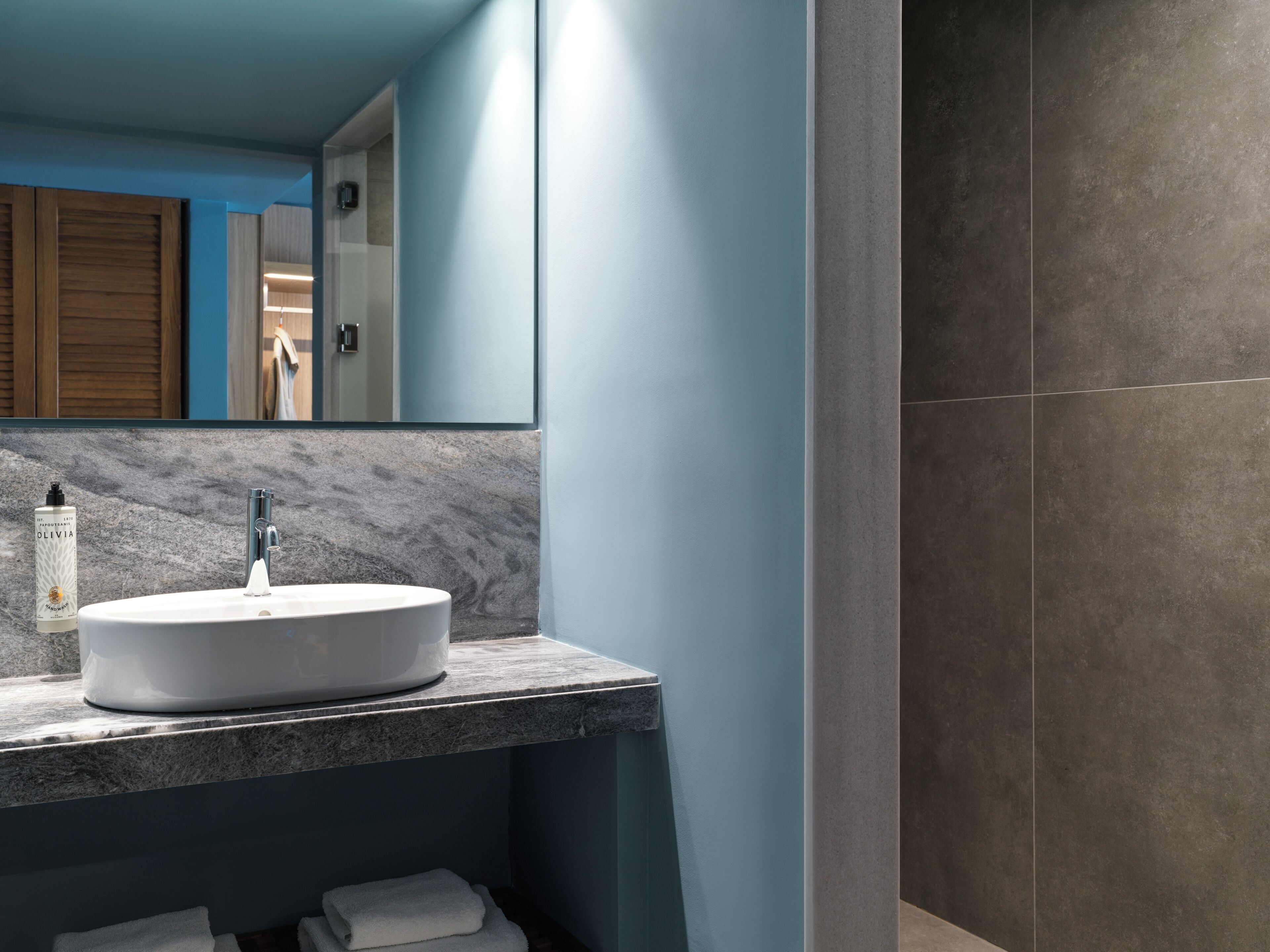 Une salle de bain moderne avec un grand miroir, un lavabo blanc et un plan de toilette en marbre.