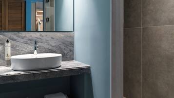 Une salle de bain moderne avec un grand miroir, un lavabo blanc et un plan de toilette en marbre.