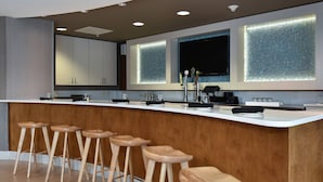 A modern kitchen with a wooden bar area, bar stools, and built-in appliances. - SpringHill Suites by Marriott Columbia Downtown/The Vista (Columbia)