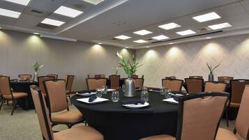 A conference room with a round table, chairs, and a potted plant.