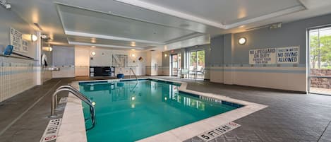 Une piscine intérieure à l’eau claire, avec des murs carrelés et des panneaux de signalisation de sécurité.