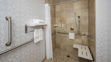 Un baño moderno con ducha, barras de apoyo y un perchero para toallas.