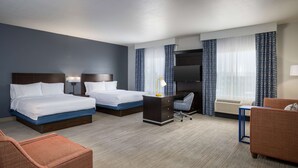 Una habitación de hotel con dos camas, un escritorio, una silla y un sofá.