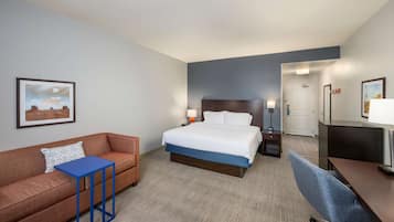 A hotel room with a bed, a sofa, a desk, and a chair.